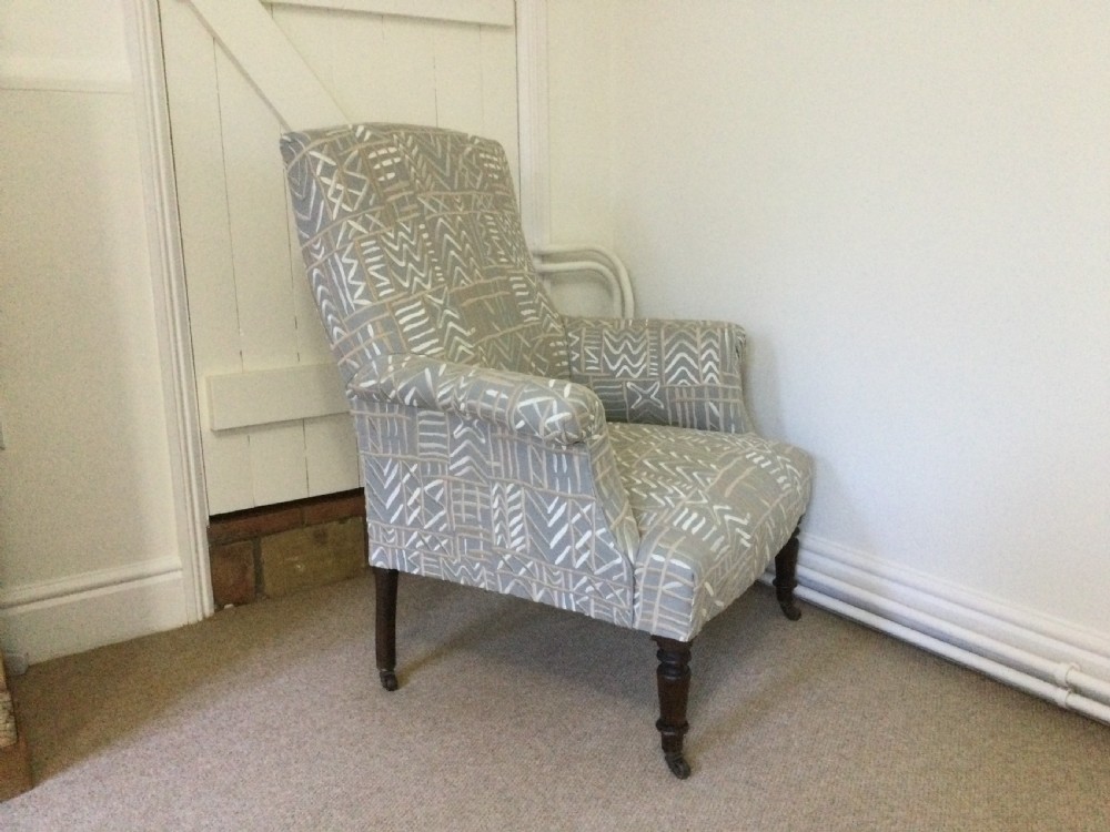 A 19th-century French armchair re-upholstered in a grey and white geometric patterned fabric with dark turned wood front legs on castors. View II