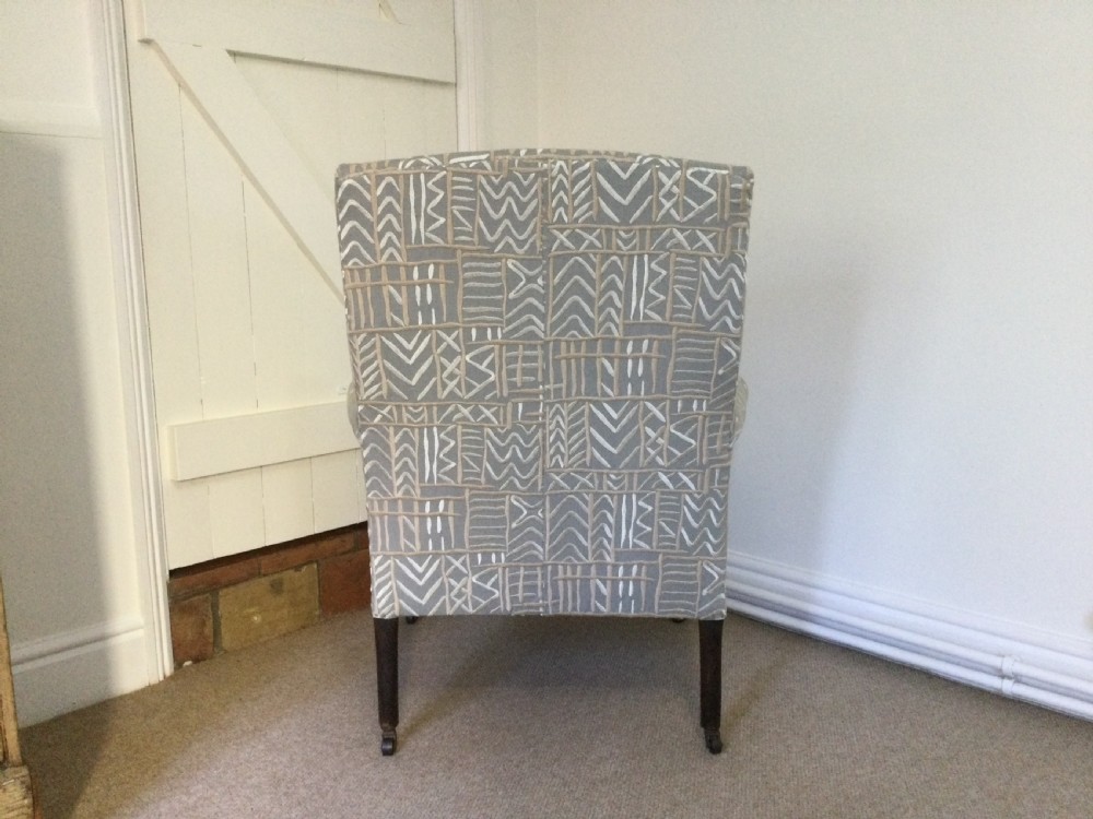 A 19th-century French armchair re-upholstered in a grey and white geometric patterned fabric with dark turned wood front legs on castors. View IV