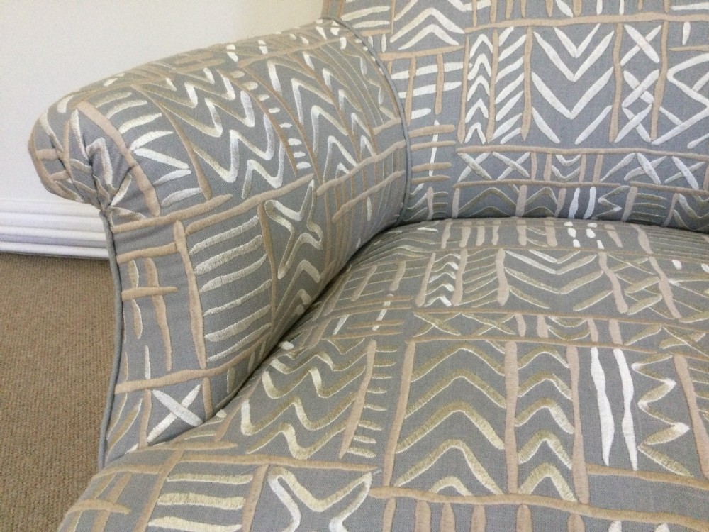 A 19th-century French armchair re-upholstered in a grey and white geometric patterned fabric with dark turned wood front legs on castors. View V
