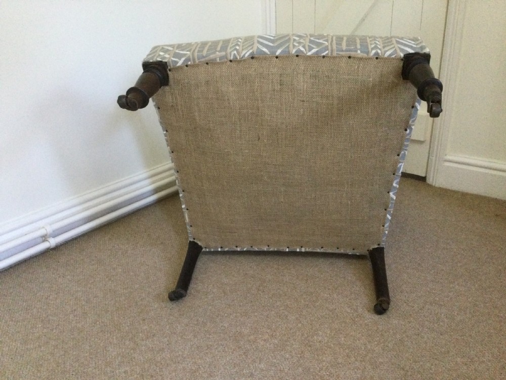 A 19th-century French armchair re-upholstered in a grey and white geometric patterned fabric with dark turned wood front legs on castors. View VII