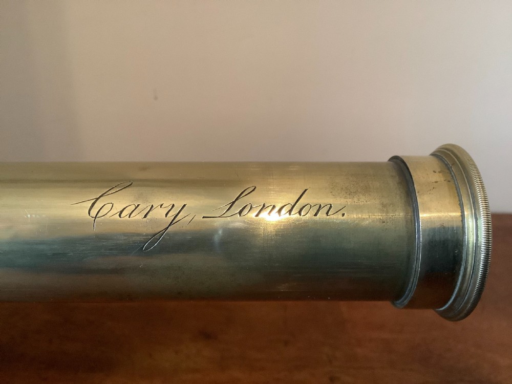 An antique brass multi-draw telescope with a leather-bound barrel rested horizontally on a fitted wooden display stand. View II