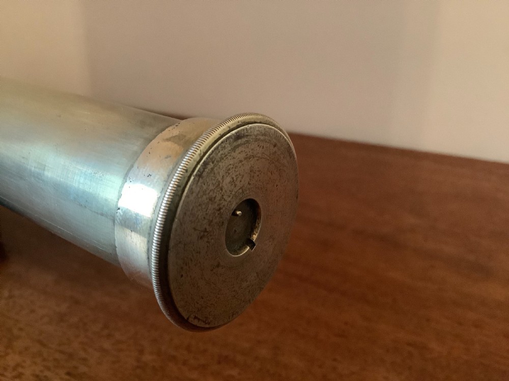 An antique brass multi-draw telescope with a leather-bound barrel rested horizontally on a fitted wooden display stand. View VI