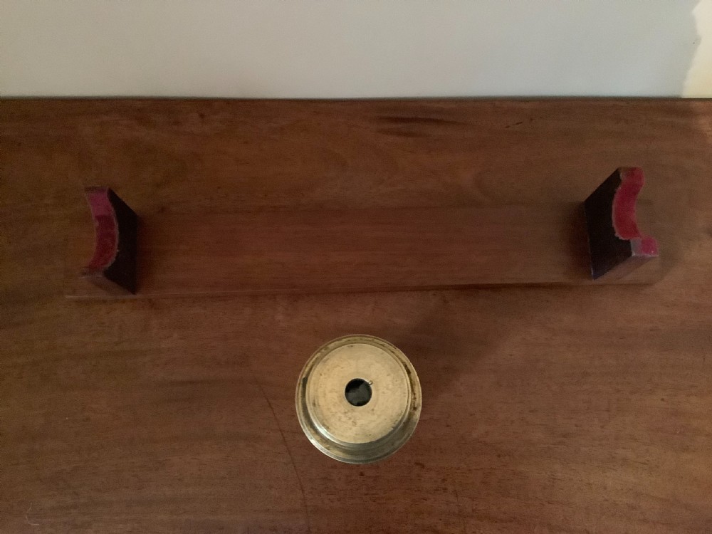 An antique brass multi-draw telescope with a leather-bound barrel rested horizontally on a fitted wooden display stand. View X