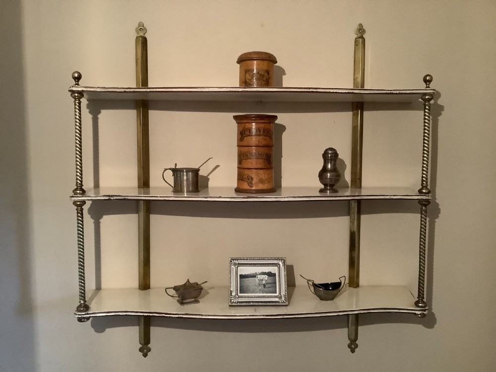 A three-tier off-white painted wood wall shelf unit featuring turned spiral brass side supports and vertical mounting rails. View II