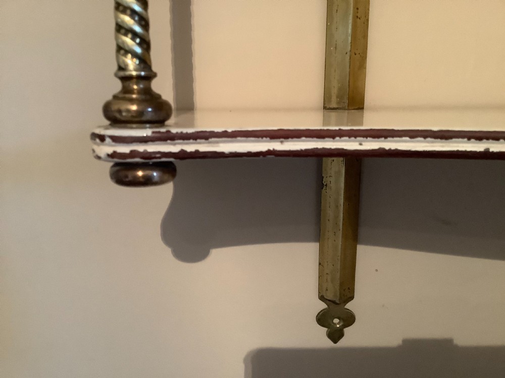 A three-tier off-white painted wood wall shelf unit featuring turned spiral brass side supports and vertical mounting rails. View VI