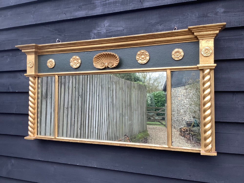 A 19th-century giltwood triple plate overmantel mirror featuring spiral-twist side columns, a dark painted frieze with gold rosettes, and a central carved shell motif.