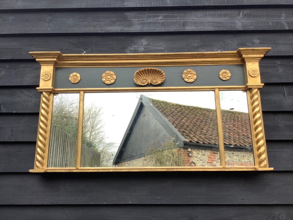 A 19th-century giltwood triple plate overmantel mirror featuring spiral-twist side columns, a dark painted frieze with gold rosettes, and a central carved shell motif. View V