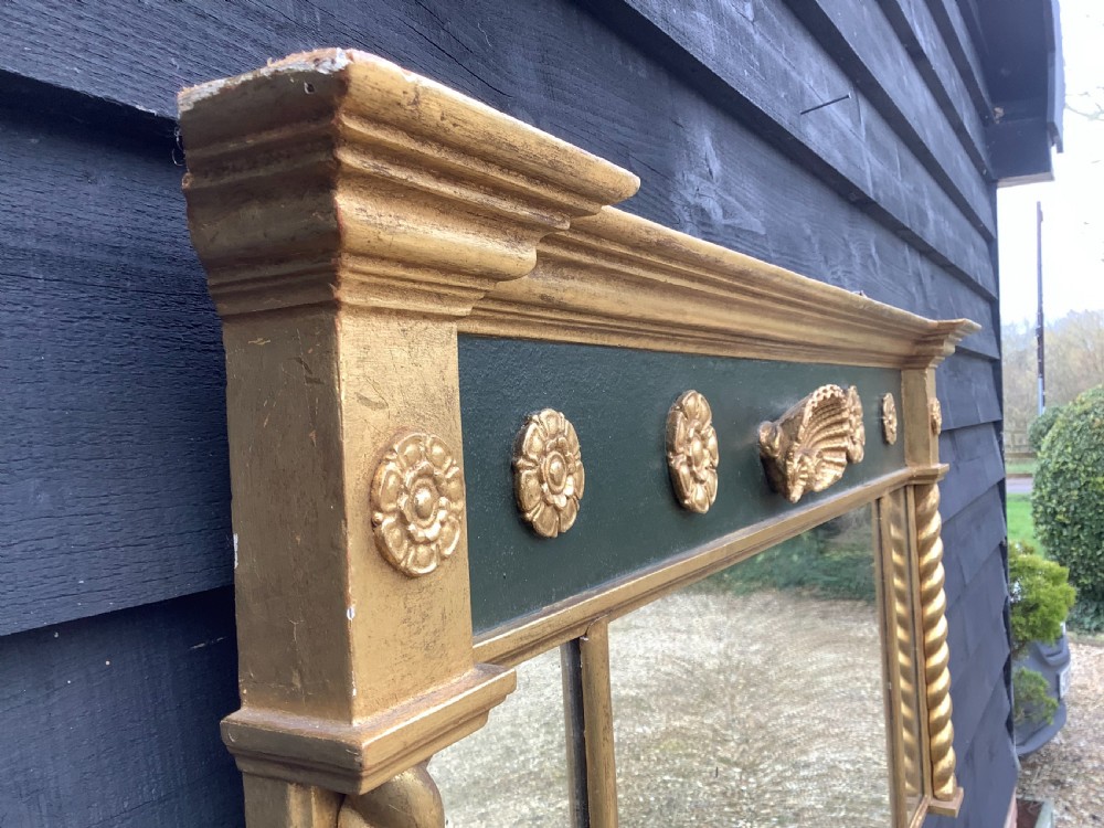 A 19th-century giltwood triple plate overmantel mirror featuring spiral-twist side columns, a dark painted frieze with gold rosettes, and a central carved shell motif. View VII