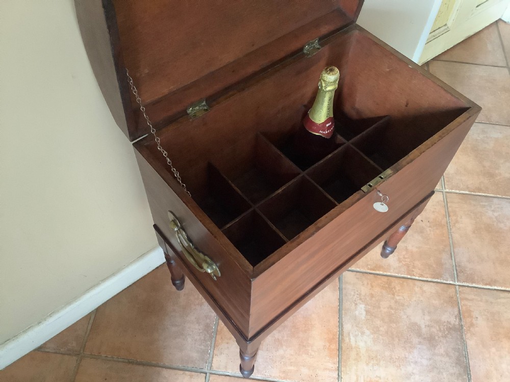 A Georgian mahogany cellarette featuring a domed lid, turned legs, flame mahogany wood grain, and side brass handles. View XI