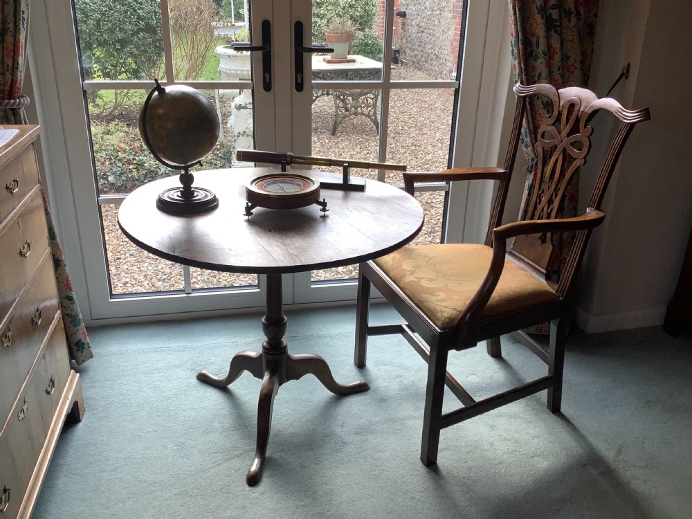 A circular antique brass and wood desk compass with adjustable levelling feet resting on a wooden surface. View II
