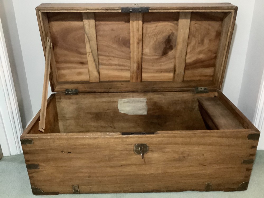 A rectangular camphor wood campaign trunk featuring flush brass corner brackets, central brass escutcheon, side carrying handles, and visible dovetail joinery. View II