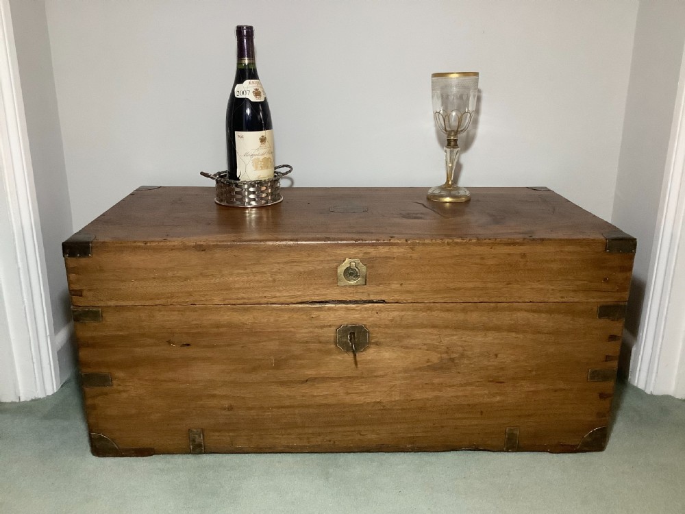 A rectangular camphor wood campaign trunk featuring flush brass corner brackets, central brass escutcheon, side carrying handles, and visible dovetail joinery. View III