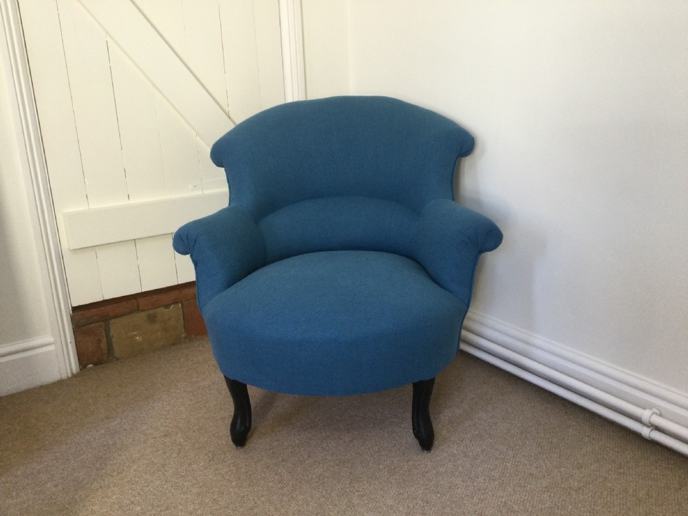 A 19th-century French crapaud armchair upholstered in teal blue fabric with dark wooden legs.