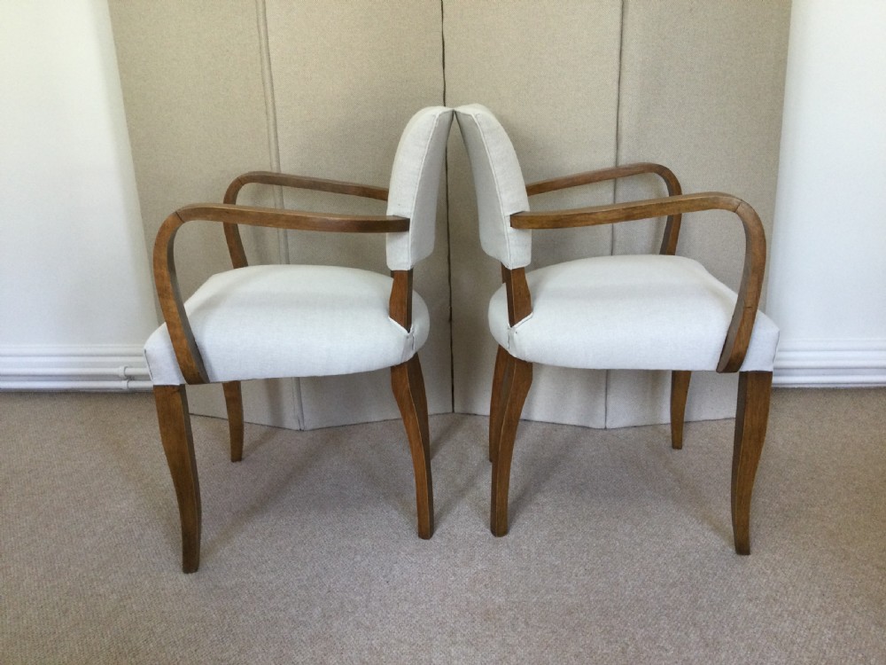A pair of French Art Deco bridge chairs featuring curved wooden arms and light beige fabric upholstery. View V