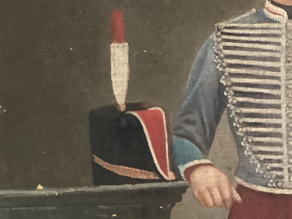 An antique full-length oil painting on canvas depicting a Hussar military officer standing in a braided blue uniform beside a pedestal. View III
