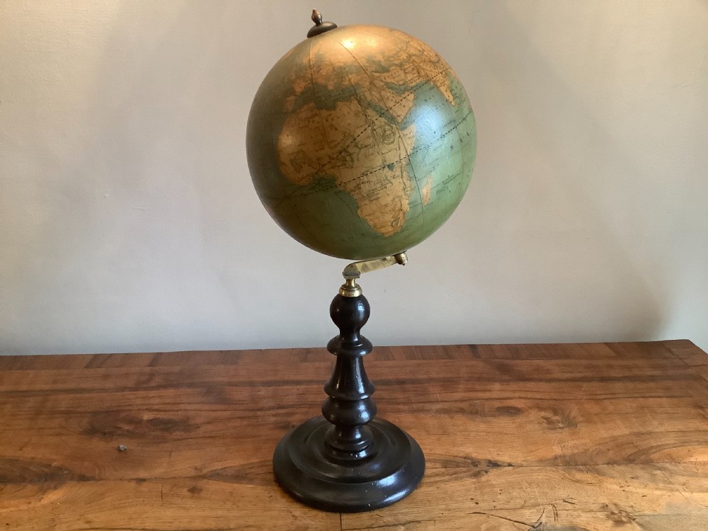 A small 19th-century French terrestrial globe with green oceans, mounted on a turned ebonised wood stand with brass fittings.