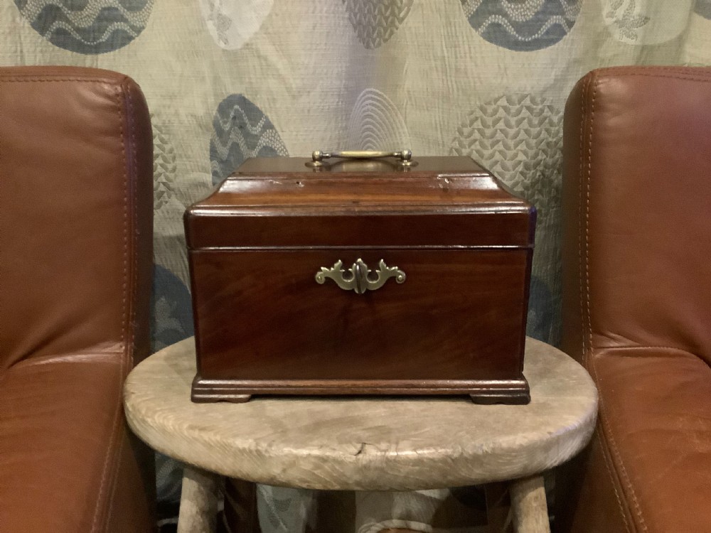 A rectangular Georgian mahogany tea caddy featuring a hinged lid, a brass top carrying handle, and an ornate brass keyhole escutcheon.