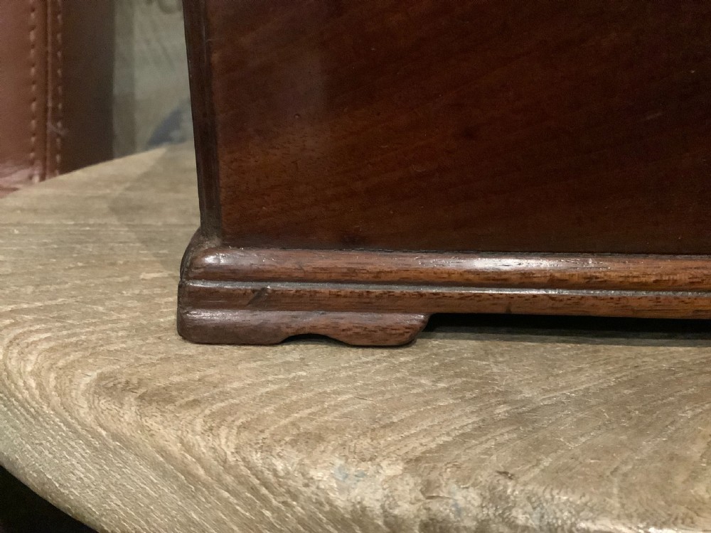 A rectangular Georgian mahogany tea caddy featuring a hinged lid, a brass top carrying handle, and an ornate brass keyhole escutcheon. View V