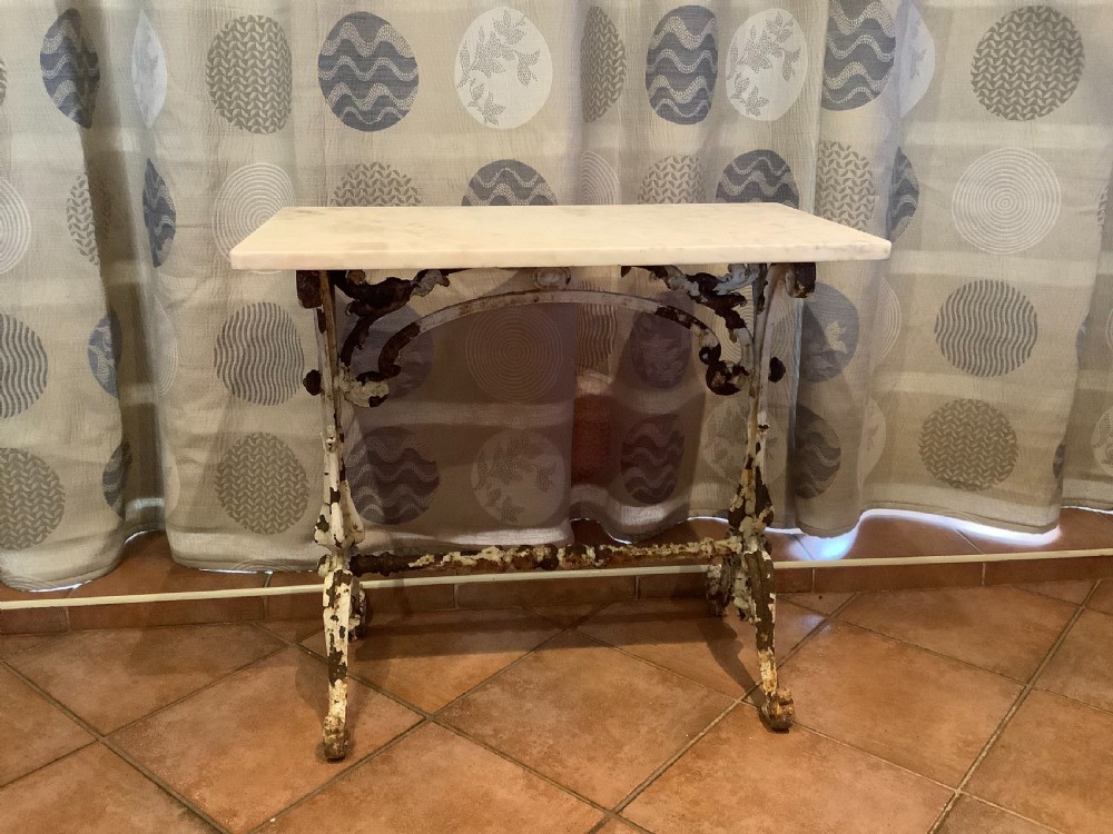 A nineteenth-century console table featuring a rectangular white marble top supported by a distressed white-painted cast iron base with ornate scrollwork.