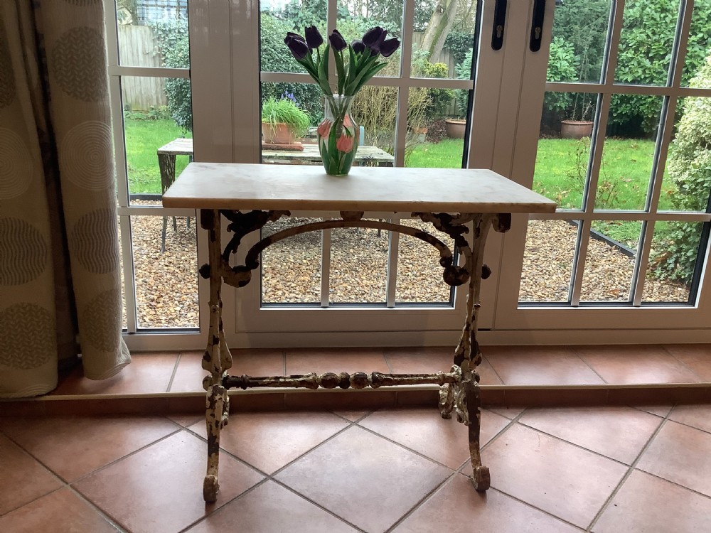 A nineteenth-century console table featuring a rectangular white marble top supported by a distressed white-painted cast iron base with ornate scrollwork. View II