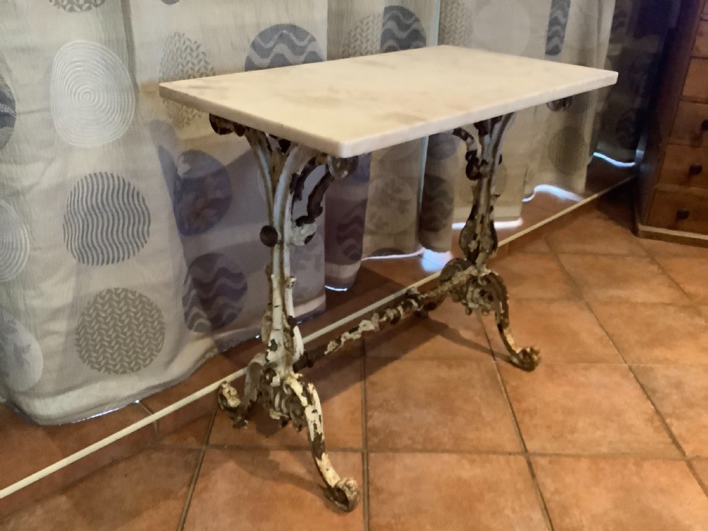 A nineteenth-century console table featuring a rectangular white marble top supported by a distressed white-painted cast iron base with ornate scrollwork. View V