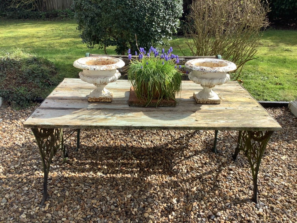 A pair of weathered off-white cast iron table urns featuring classical gadrooned decoration and square pedestal bases. View II