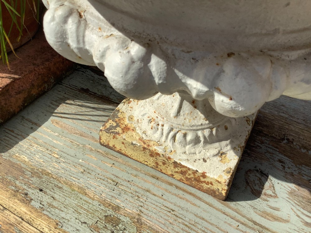 A pair of weathered off-white cast iron table urns featuring classical gadrooned decoration and square pedestal bases. View XIII