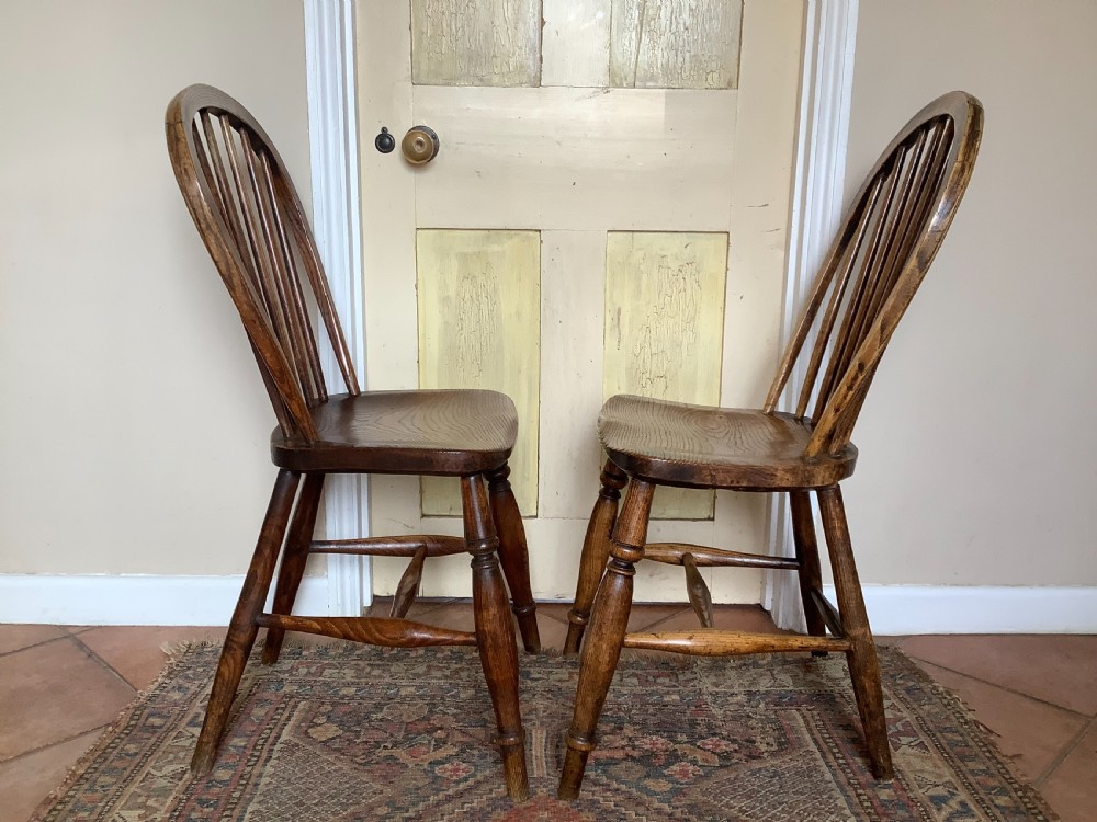 A near pair of antique wooden stick back Windsor kitchen chairs with hoop backs and turned legs. View II