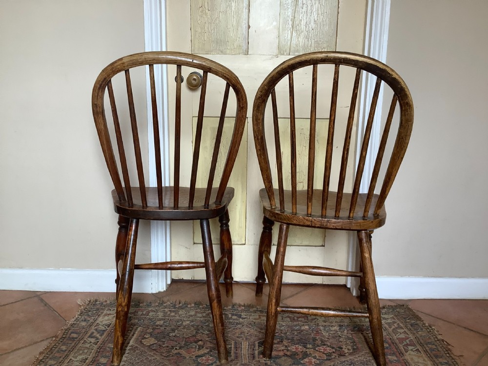 A near pair of antique wooden stick back Windsor kitchen chairs with hoop backs and turned legs. View III