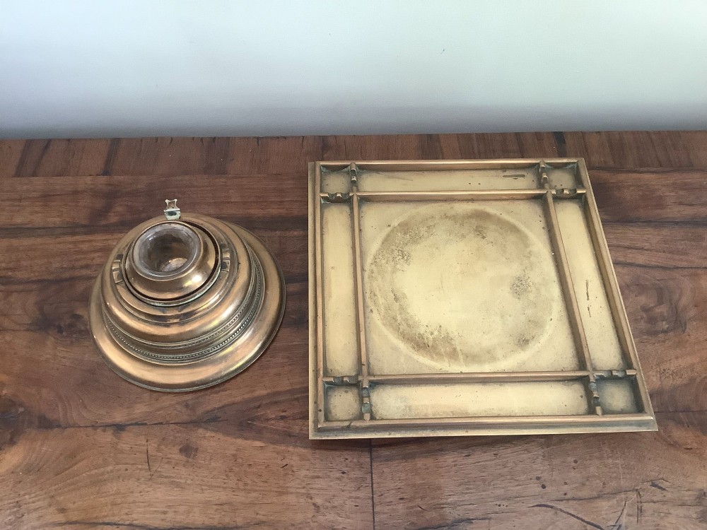 A square Victorian brass inkstand featuring a central domed hinged inkwell resting on a stepped base surrounded by pen channels. View III