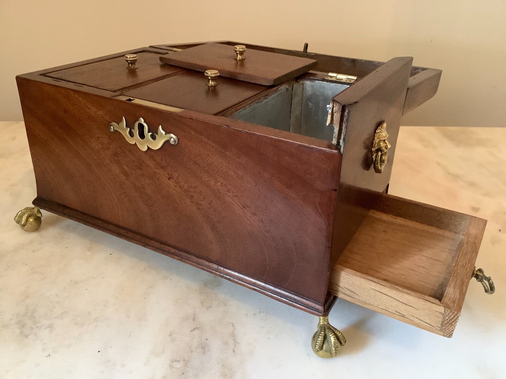 A Georgian mahogany tea caddy featuring brass ball-and-claw feet, a central brass escutcheon, and a top carrying handle. View IV