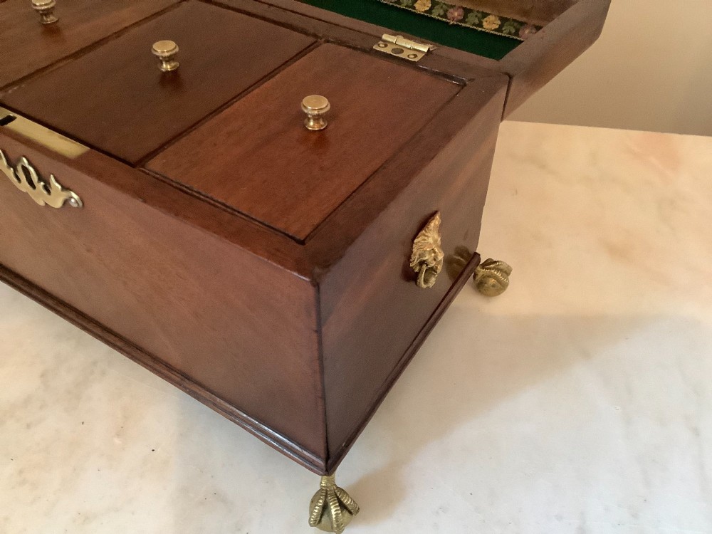 A Georgian mahogany tea caddy featuring brass ball-and-claw feet, a central brass escutcheon, and a top carrying handle. View VI