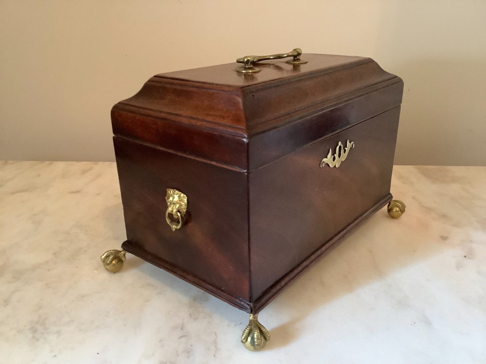 A Georgian mahogany tea caddy featuring brass ball-and-claw feet, a central brass escutcheon, and a top carrying handle. View VIII
