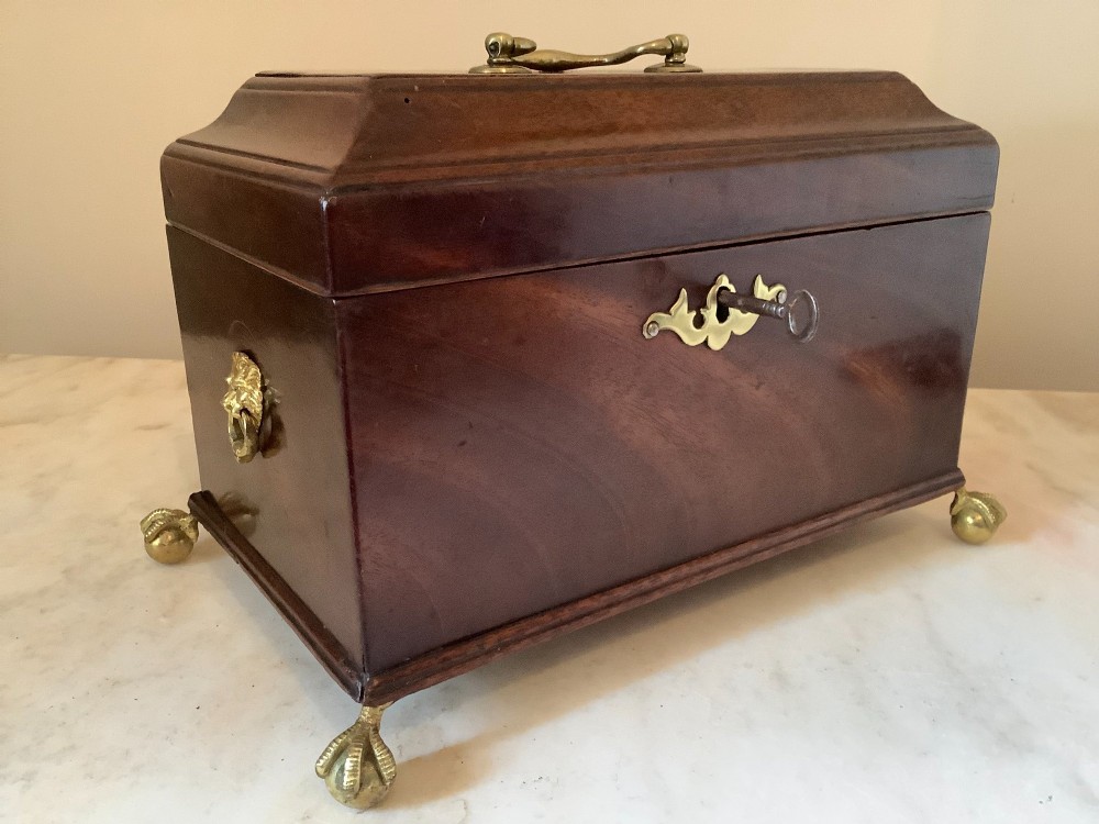 A Georgian mahogany tea caddy featuring brass ball-and-claw feet, a central brass escutcheon, and a top carrying handle. View XV