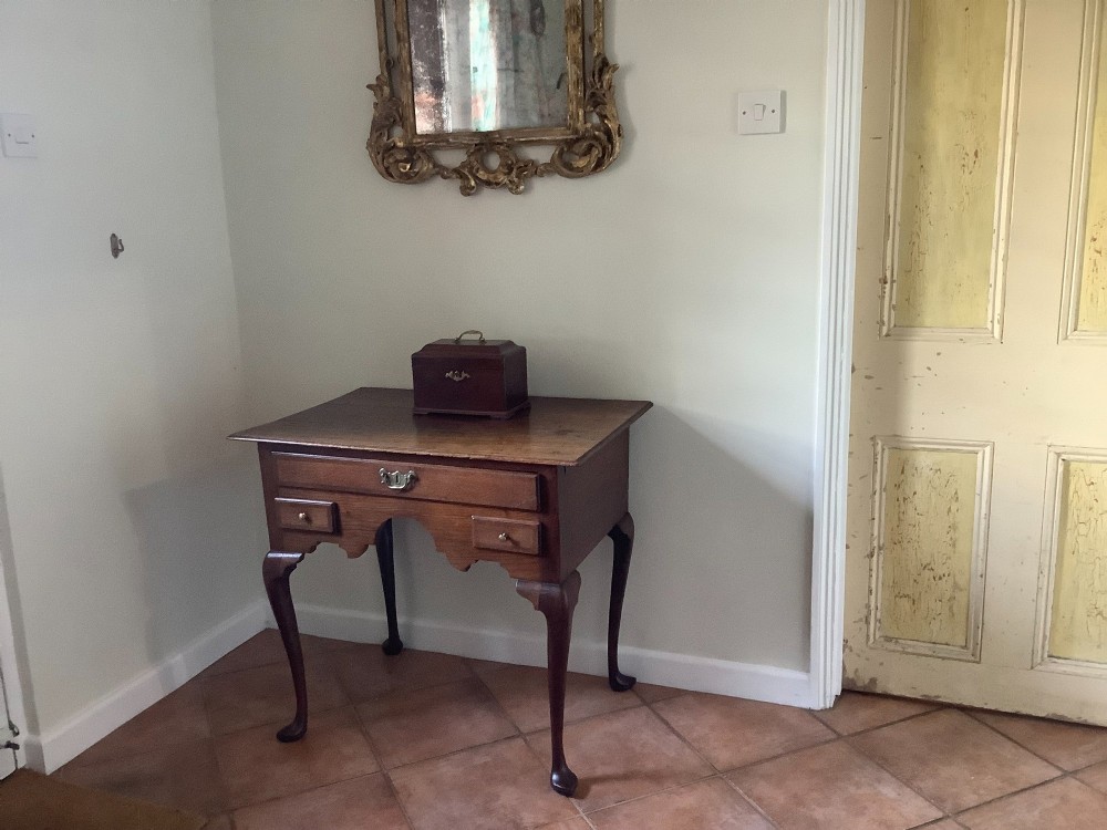 An 18th-century oak lowboy featuring a three-drawer configuration above an arched apron and cabriole legs ending in pad feet. View II