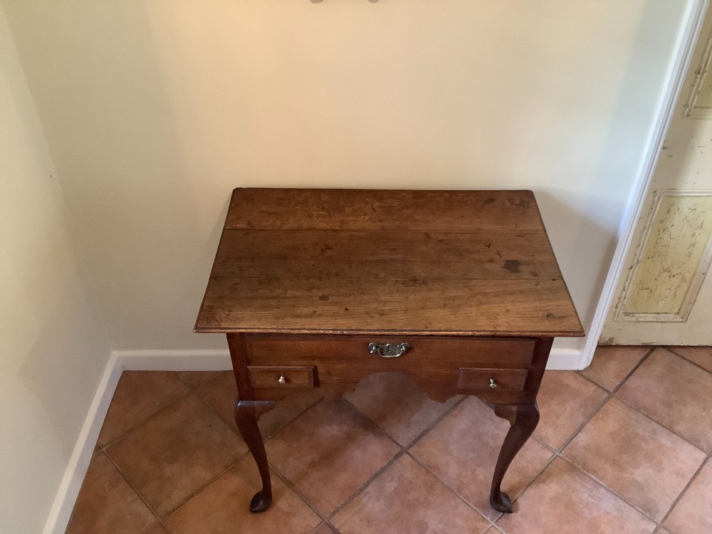 An 18th-century oak lowboy featuring a three-drawer configuration above an arched apron and cabriole legs ending in pad feet. View III