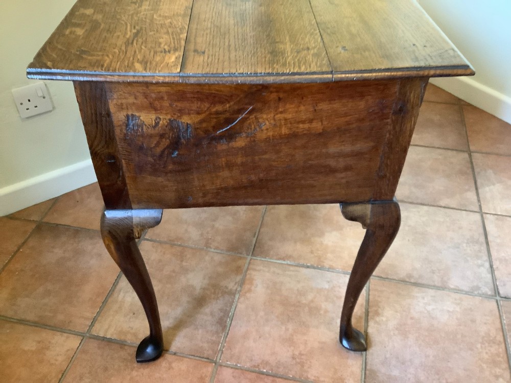 An 18th-century oak lowboy featuring a three-drawer configuration above an arched apron and cabriole legs ending in pad feet. View IX