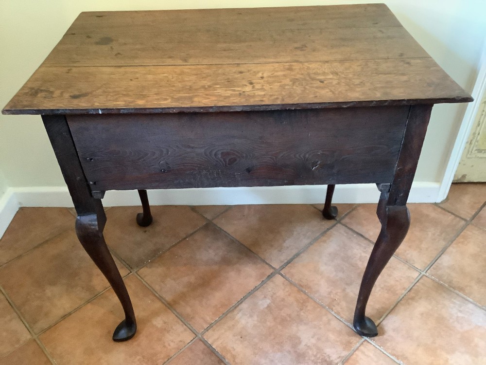 An 18th-century oak lowboy featuring a three-drawer configuration above an arched apron and cabriole legs ending in pad feet. View XI