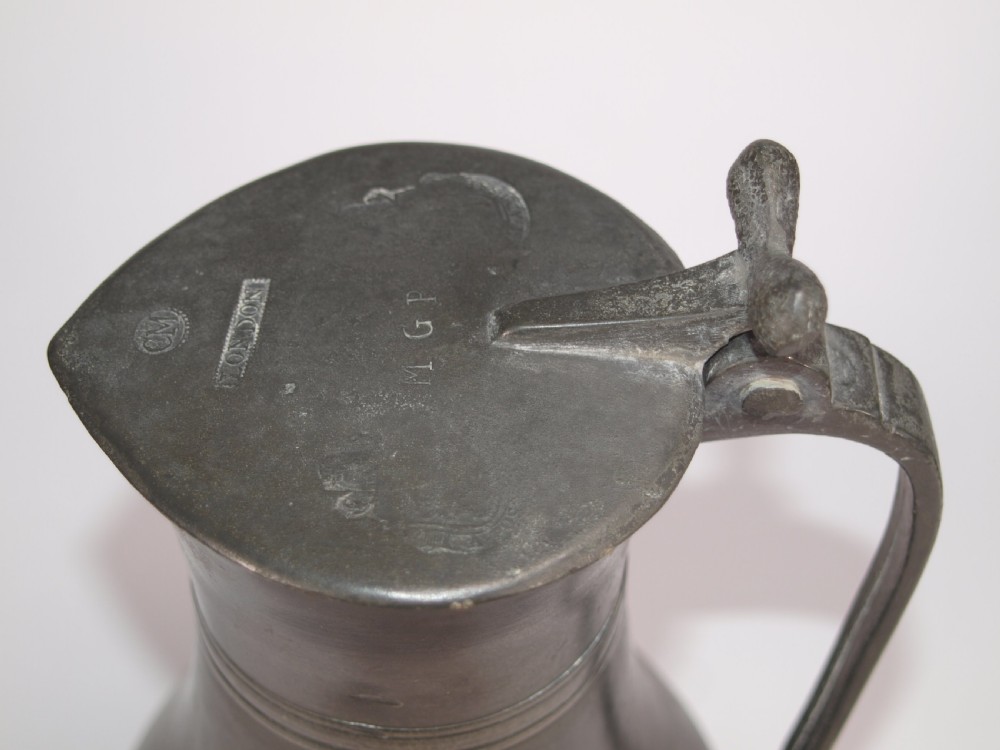 An antique dark grey pewter lidded flagon featuring a bulbous body, flared collar, hinged lid, and handle. View VI