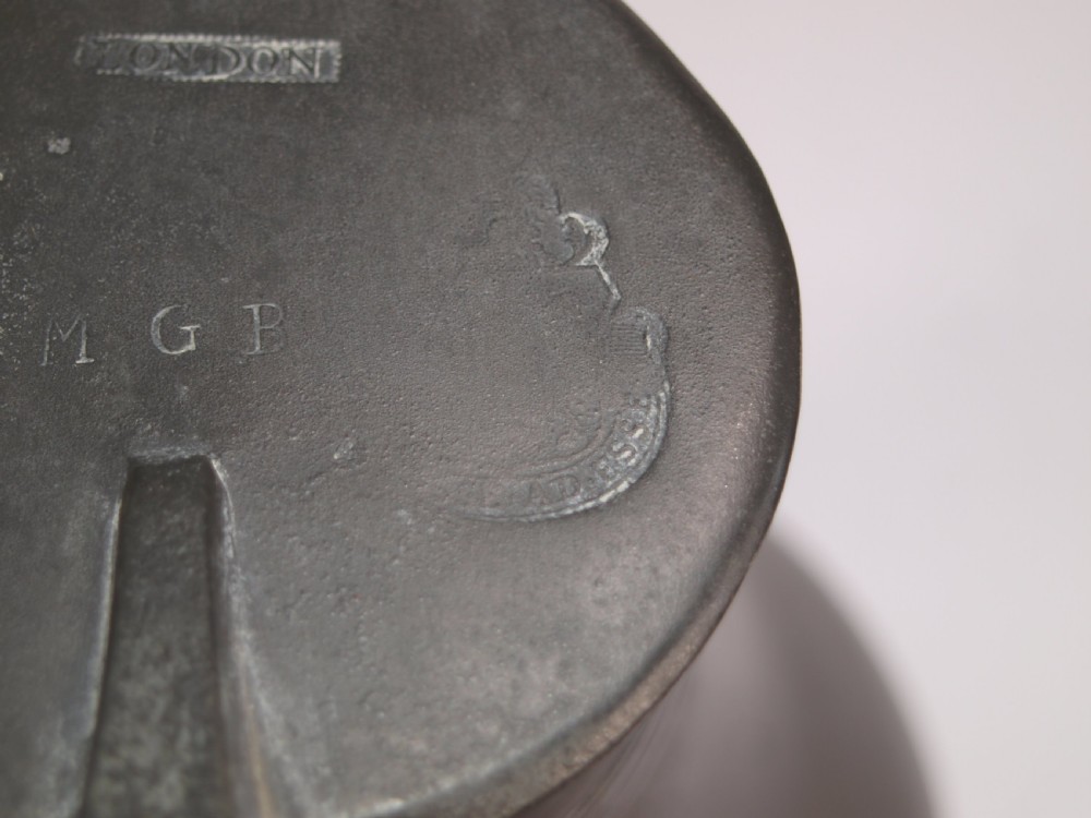 An antique dark grey pewter lidded flagon featuring a bulbous body, flared collar, hinged lid, and handle. View X