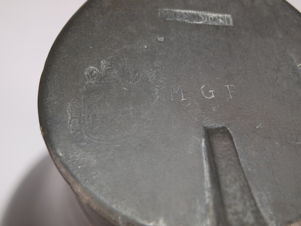 An antique dark grey pewter lidded flagon featuring a bulbous body, flared collar, hinged lid, and handle. View XI