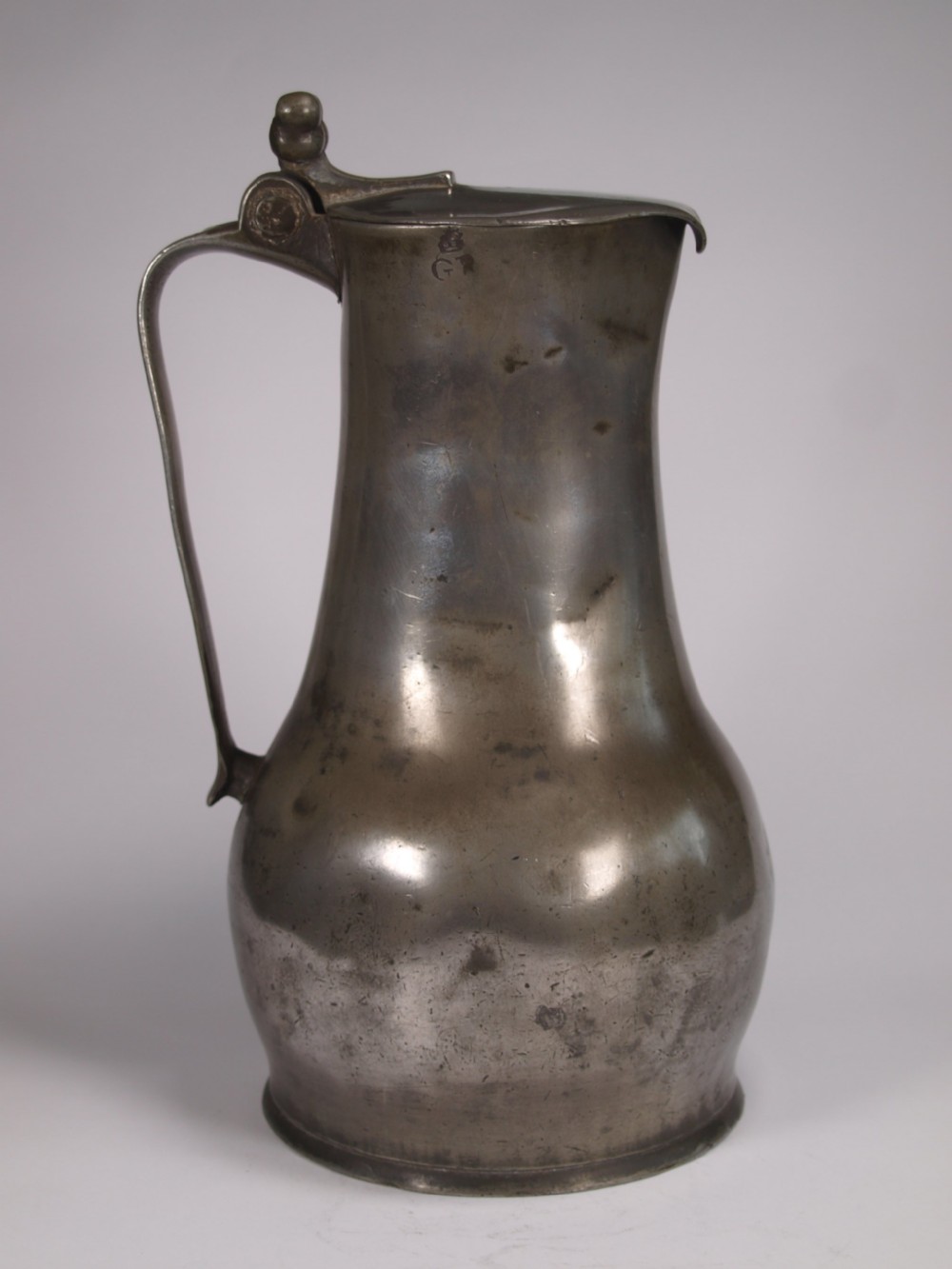 An antique pewter Jersey measure with a hinged lid, double acorn thumbpiece, curved handle, and bulbous body. View III