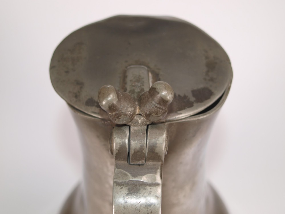An antique pewter Jersey measure with a hinged lid, double acorn thumbpiece, curved handle, and bulbous body. View VII