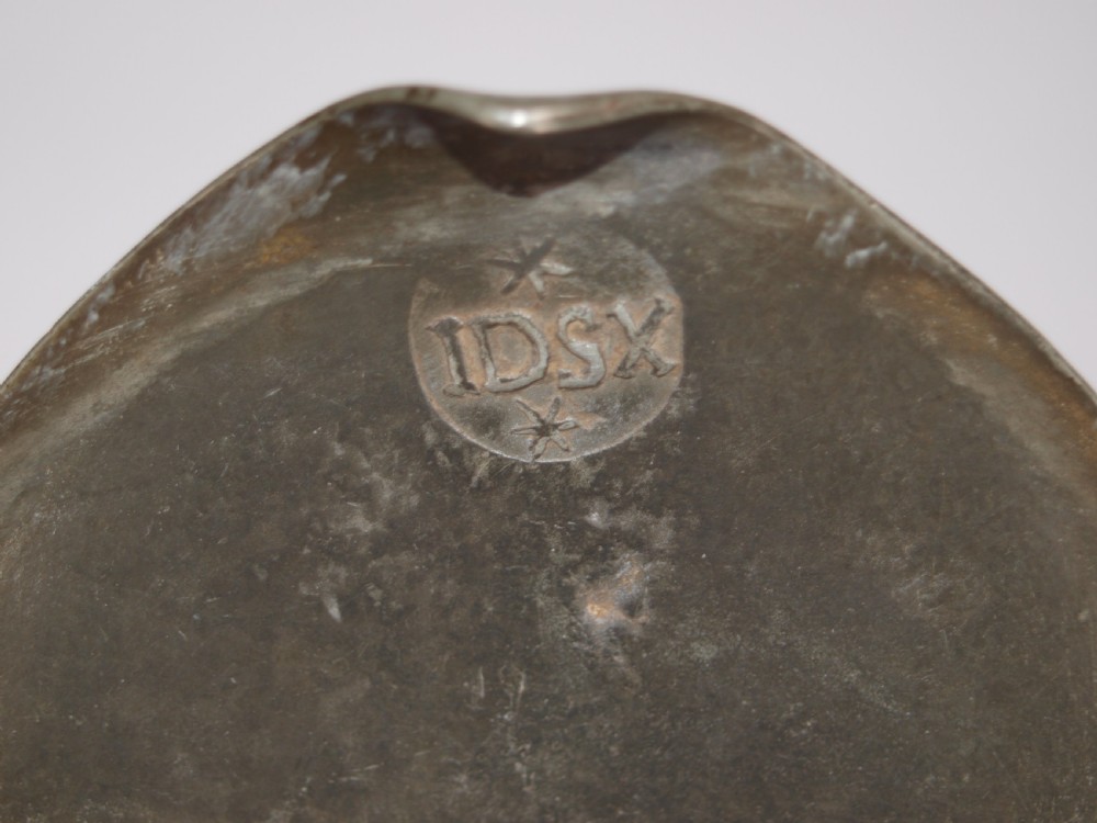An antique pewter Jersey measure with a hinged lid, double acorn thumbpiece, curved handle, and bulbous body. View XI