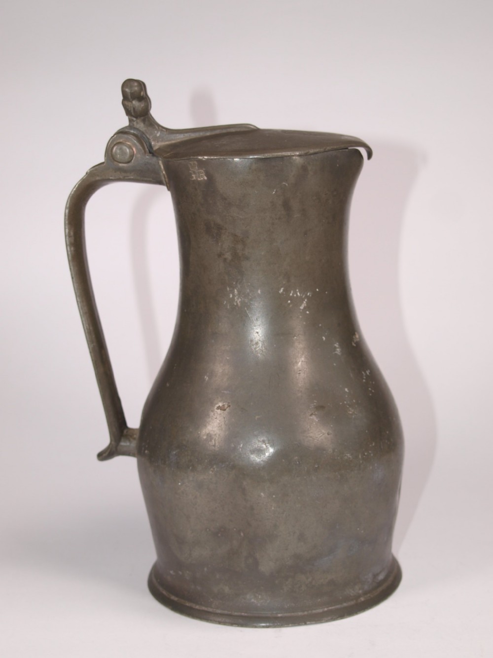 An antique slate grey pewter lidded quart measure featuring a baluster shape, attached strap handle, and hinged lid. View III