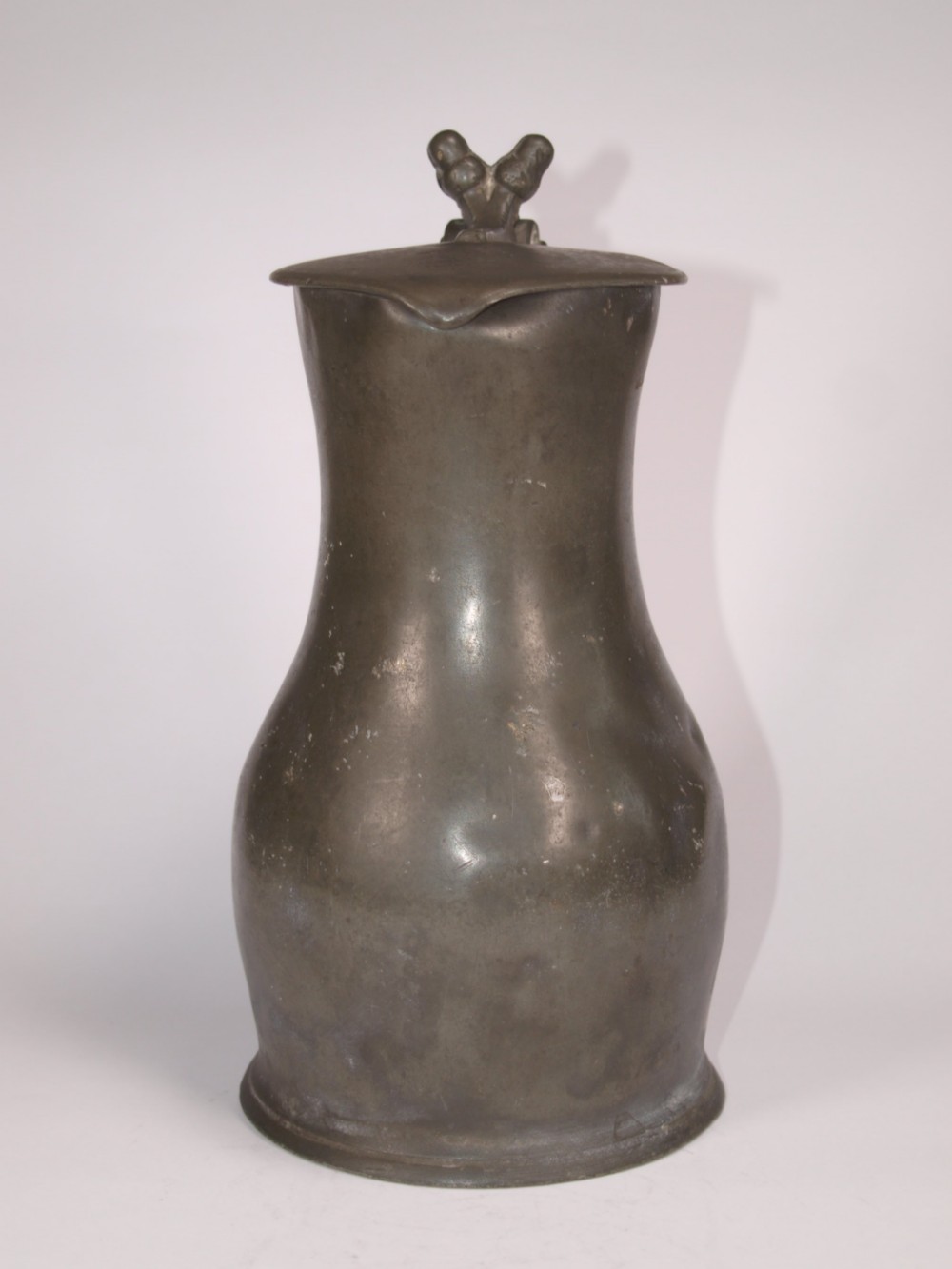 An antique slate grey pewter lidded quart measure featuring a baluster shape, attached strap handle, and hinged lid. View V