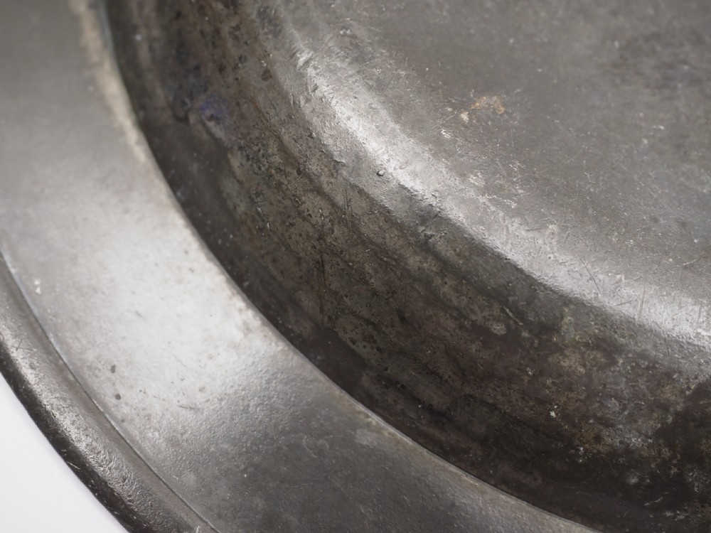 A circular grey antique pewter deep plate featuring a wide plain rim engraved with monogrammed initials at the top and the date 1845 at the bottom. View VII
