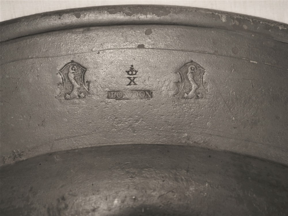 A circular 18th-century English pewter charger featuring a broad plain rim and an aged patinated surface. View IV