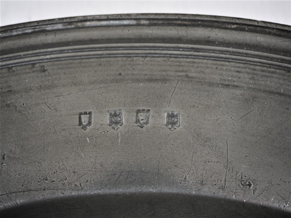 A circular 17th-century pewter charger plate featuring a wide rim decorated with triple reeded moulding and visible maker touchmarks. View III