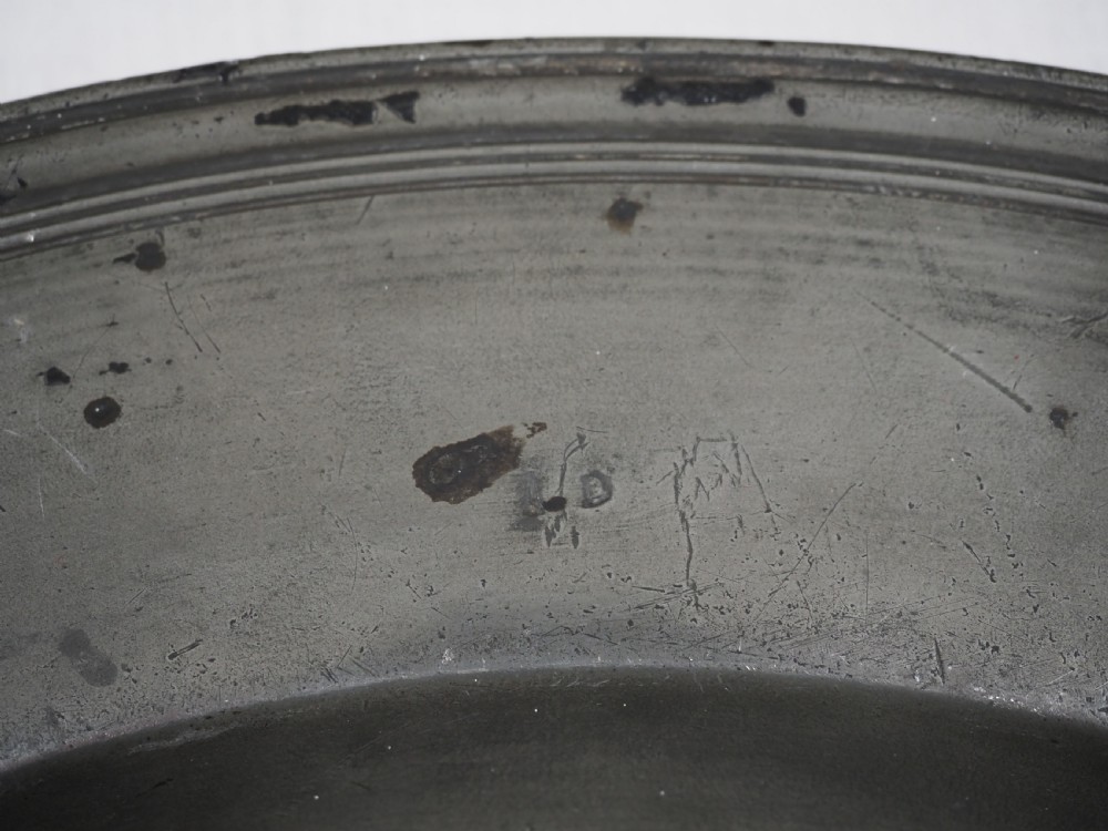 A circular 17th-century pewter charger plate featuring a wide rim decorated with triple reeded moulding and visible maker touchmarks. View VII